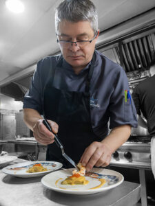 chef-preparando-plato-gourmet-restaurante-sybius-cala-canyelles-lloret-de-mar Chef emplatando un plato gourmet con marisco en la cocina del Restaurante Sybius Cala Canyelles, Lloret de Mar, Costa Brava. Xef emplatant un plat gurmet amb marisc a la cuina del Restaurant Sybius Cala Canyelles, Lloret de Mar, Costa Brava. Chef plating a gourmet seafood dish in the kitchen of Sybius Restaurant, Cala Canyelles, Lloret de Mar, Costa Brava. Chef dressant une assiette gastronomique aux fruits de mer dans la cuisine du restaurant Sybius Cala Canyelles, Lloret de Mar, Costa Brava.